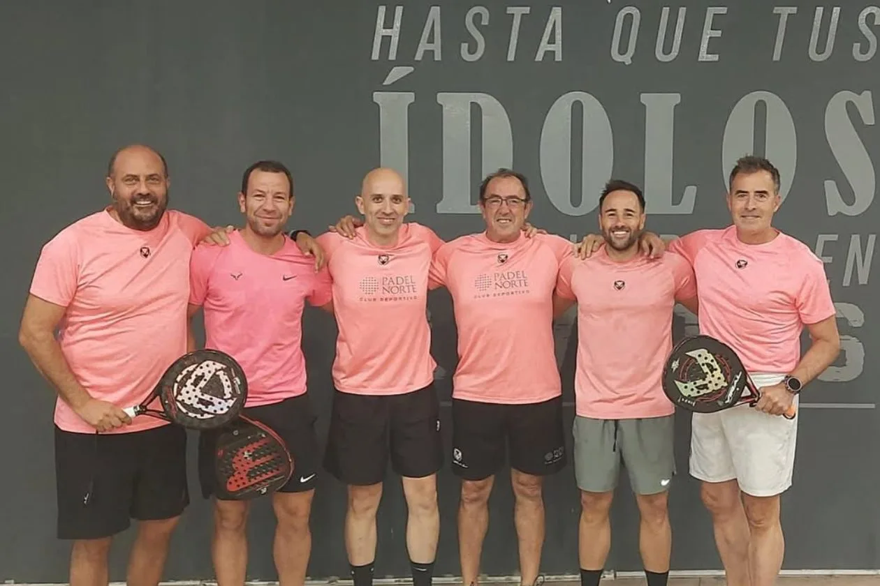 Seis jugadores posando con la camiseta oficial rosa 'Pádel Norte Club Deportivo' y palas Bullpadel frente a la pared 'Hasta que tus ídolos'